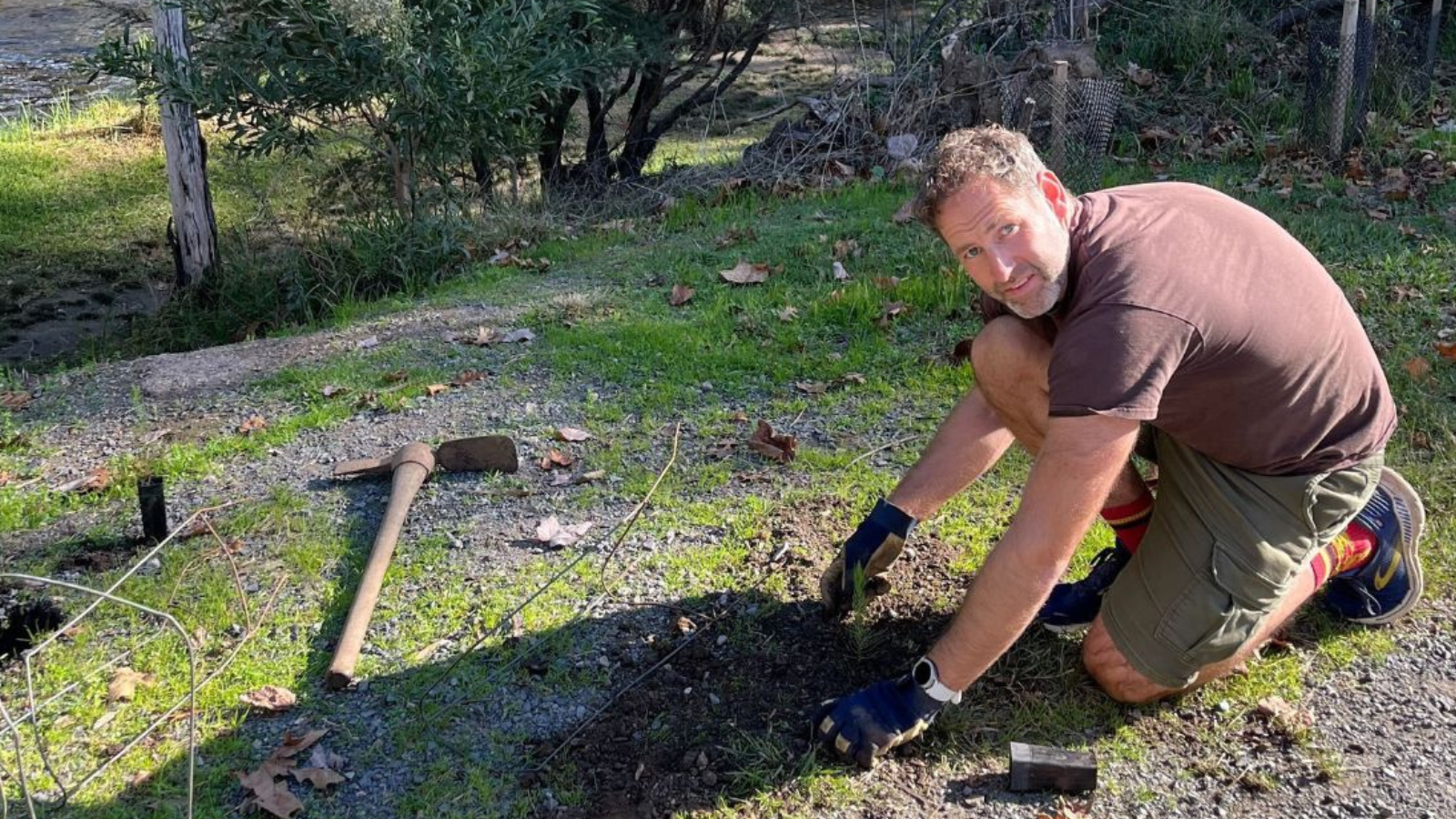 Joel planting trees along the Birrarung on the team's day by the river with Dr. Maya Ward.