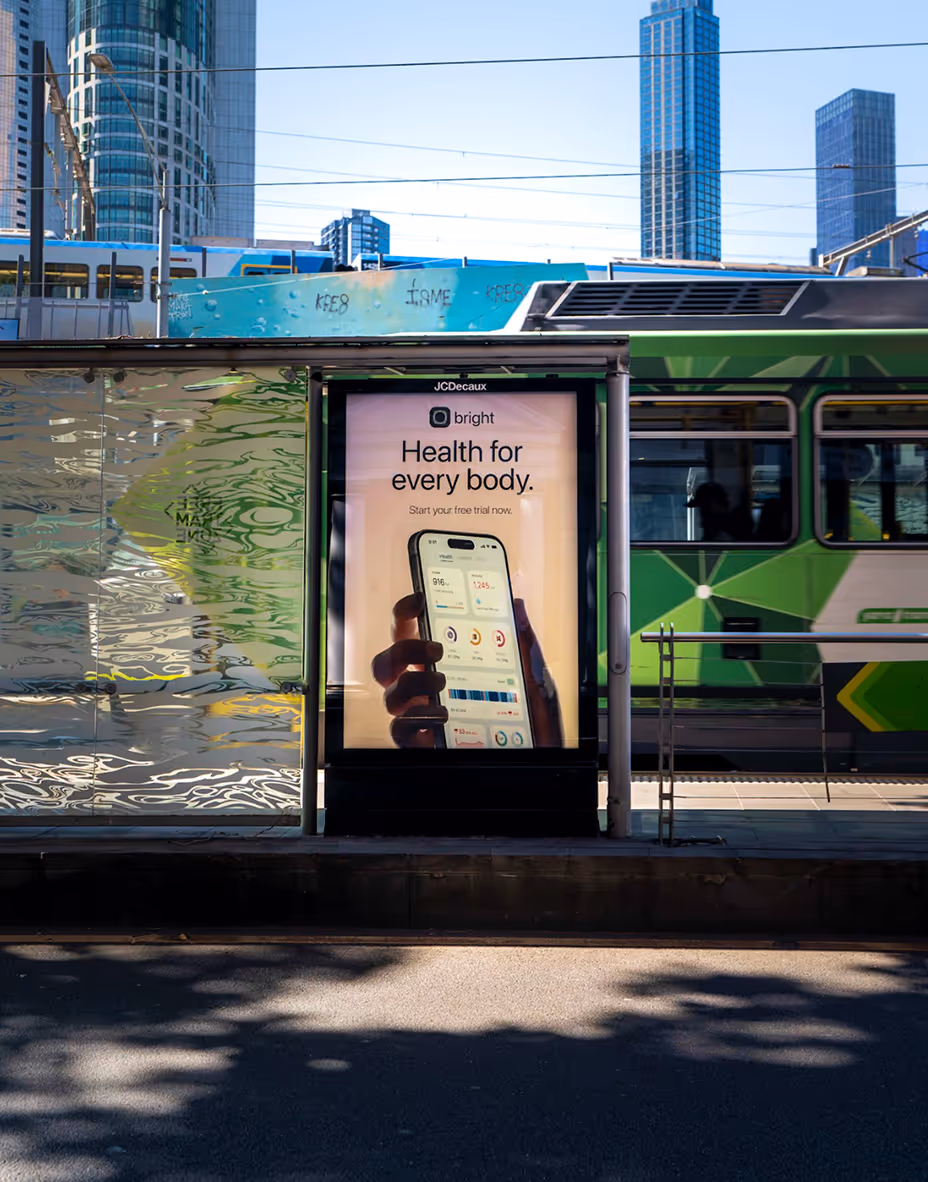 Bus stop advertisement showing a hand holding a smartphone with health app stats and text 'Health for every body. Start your free trial now.'