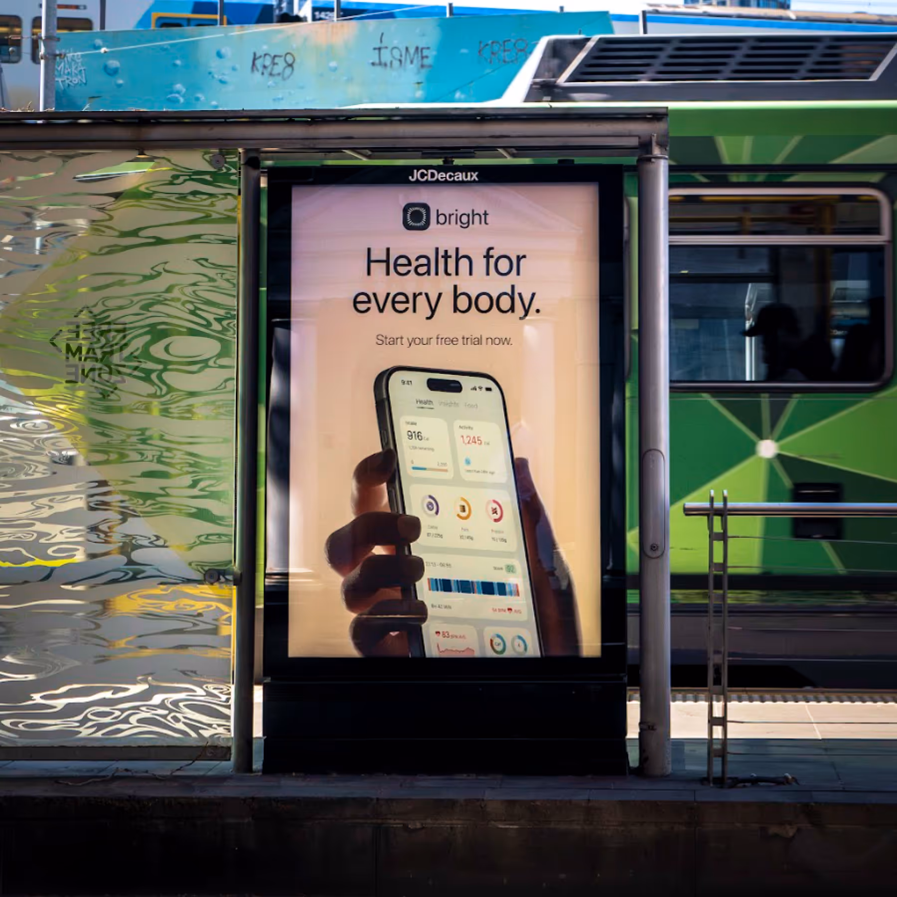 Bus stop advertisement for Bright health app showing a hand holding a phone with health tracking data, with a green bus in the background.