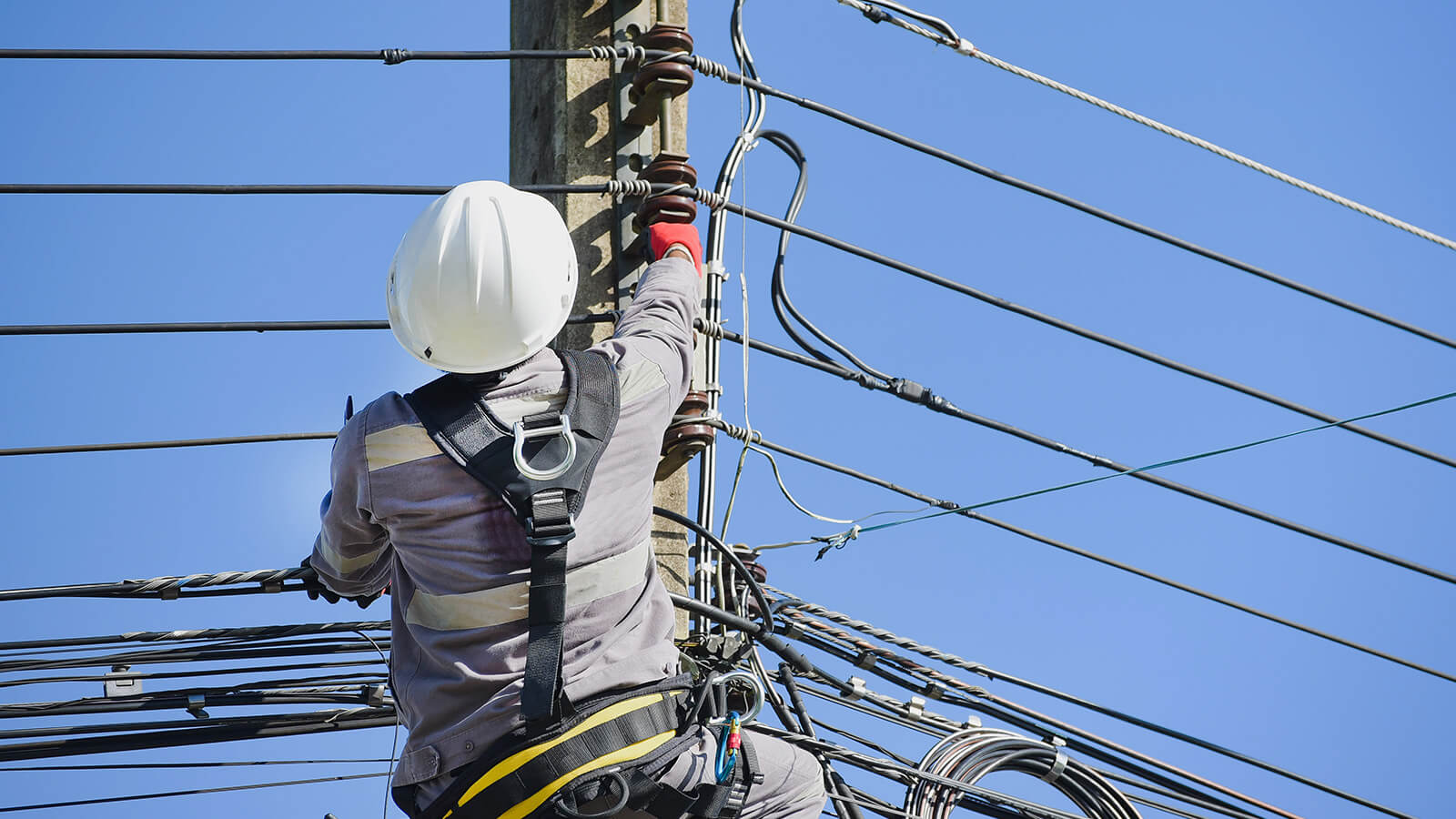 Utility lineworker performing maintenance on overhead electrical equipment.