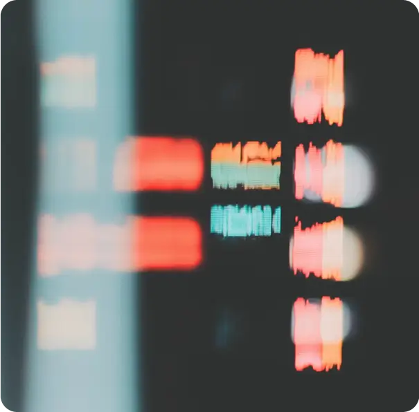 Blurred digital screen with colorful bars and text in red, orange, and teal on a dark background.