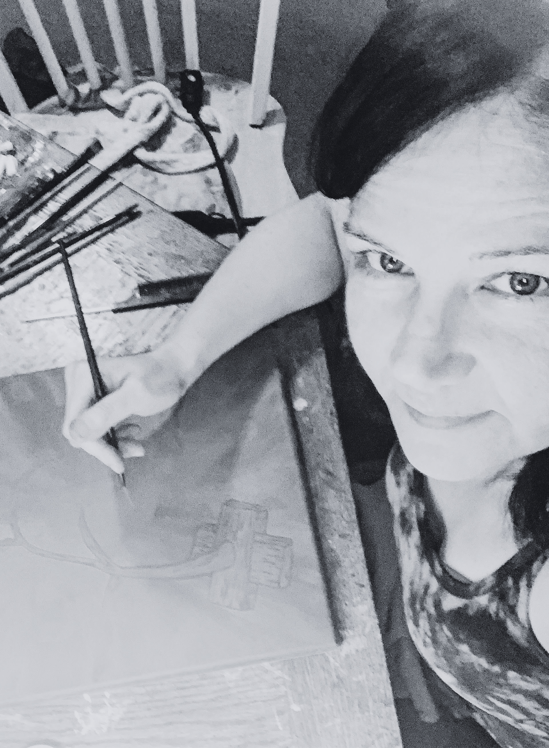 Person holding a paintbrush over a canvas on a wooden table, preparing to paint.