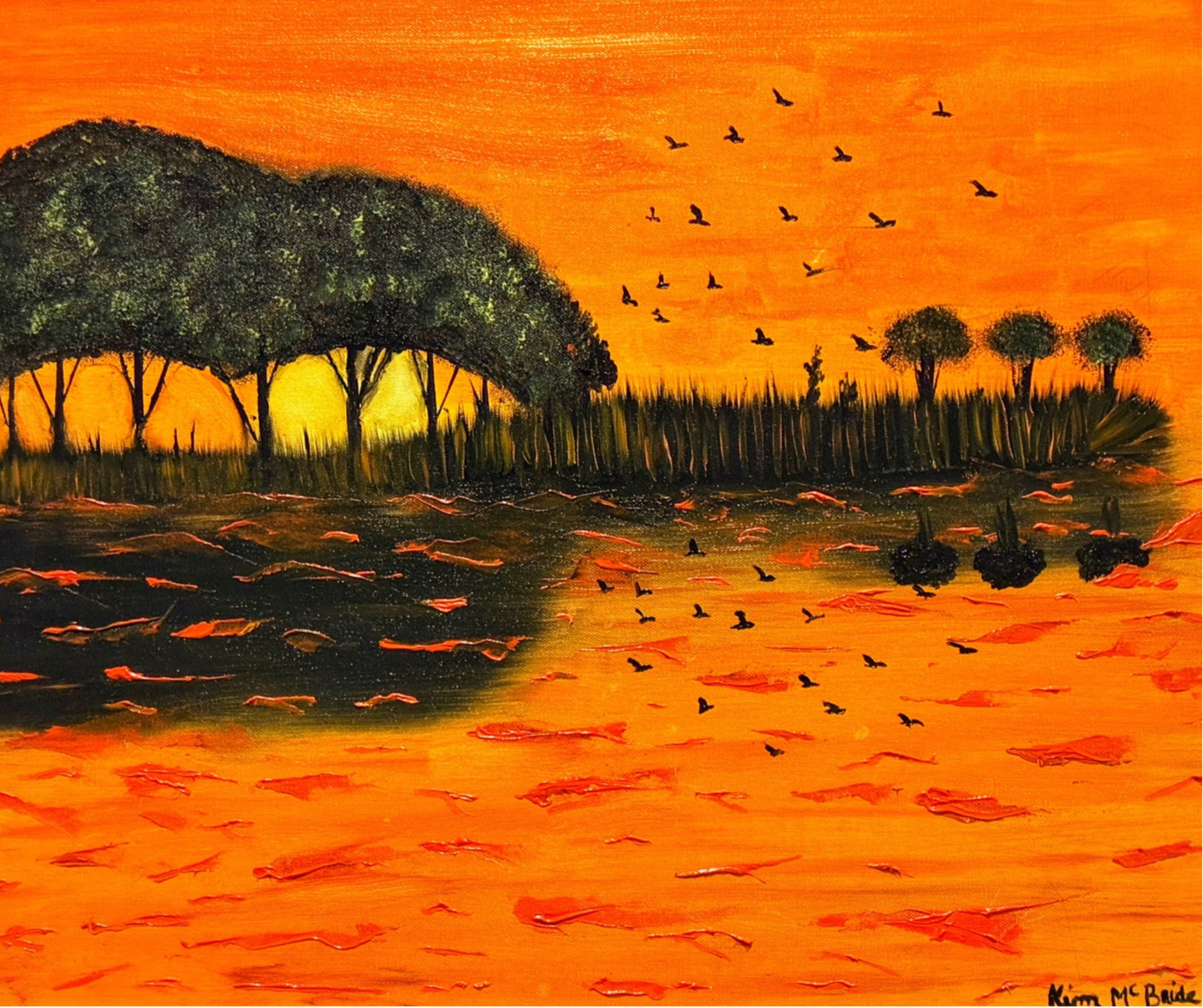 Sunset over dark water with silhouetted trees and birds flying in orange sky.