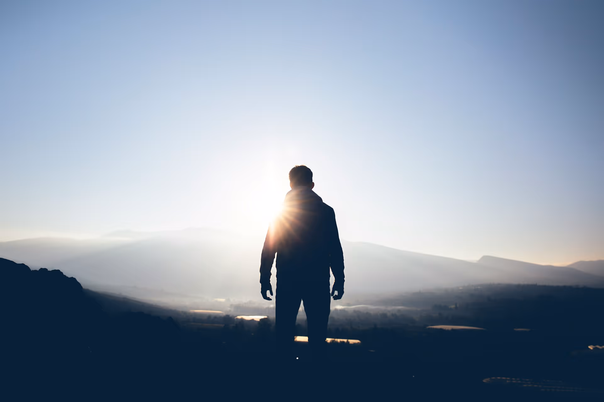 Person standing on a mountain at sunrise symbolizing mental clarity, mindfulness, and recovery.