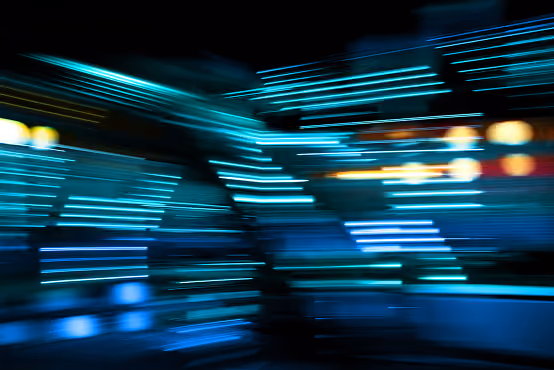 Blurred blue and teal lines of light creating an abstract dynamic pattern on dark background.