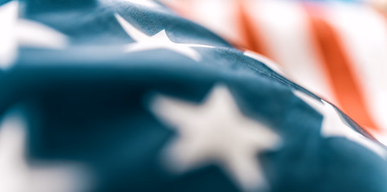 Close-up of an American flag showing blue fabric with white stars and blurred red and white stripes.