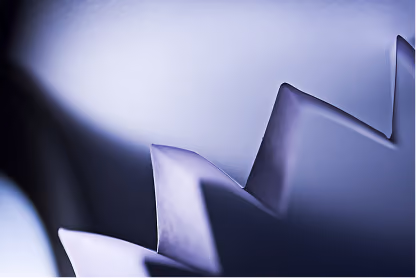 Close-up of metallic gear teeth with blue and purple lighting and soft focus edges.