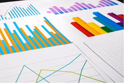 Various colorful bar and line graphs on white paper scattered on a flat surface.