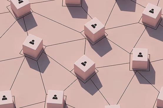 Network of light pink cubes with user icons connected by black lines on a pink surface.