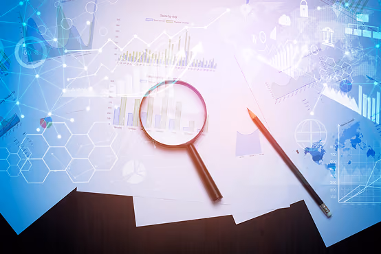 Magnifying glass and pencil on papers with charts and graphs on a dark surface with digital data overlays.