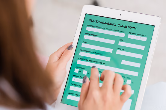 Person filling out a health insurance claim form on a white tablet screen.