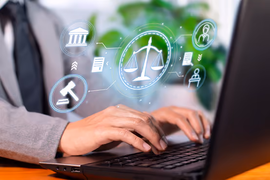 Person typing on laptop with legal icons including scales, gavel, and courthouse hovering above keyboard.