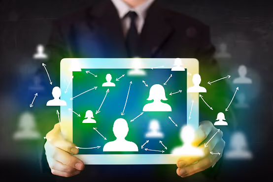 Person holding tablet showing digital network of connected user icons with arrows.