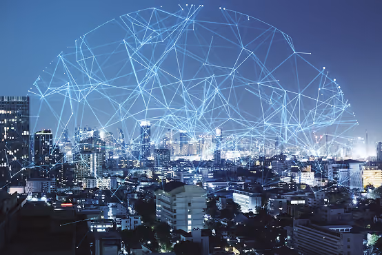 City skyline at night with digital network lines forming a cloud above buildings.