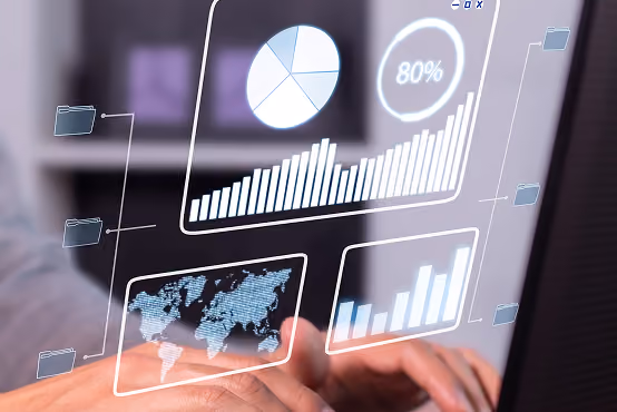 Hands typing on a laptop keyboard with transparent digital charts and graphs overlayed.