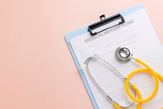 Medical history form on a blue clipboard with a yellow stethoscope on a pink surface.