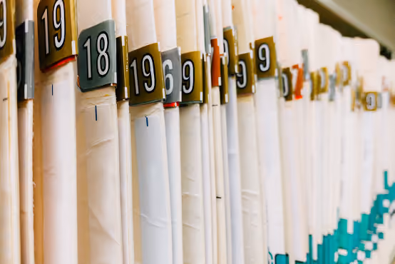 Close-up of old files with numbered labels organized in a row on a shelf.