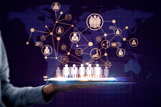 Hand holding tablet projecting digital icons of people connected by network lines over a world map.