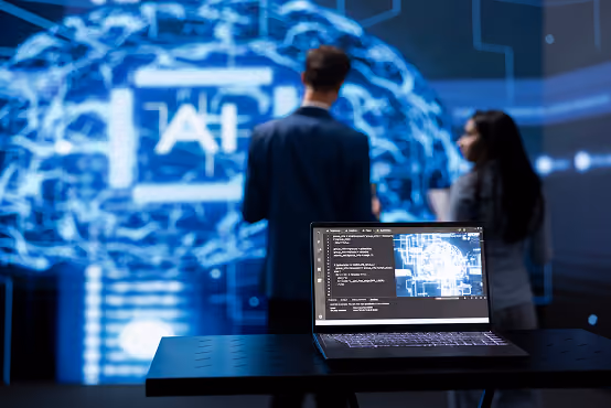 Laptop with code and brain diagram on screen in front of two people and large AI brain graphic.