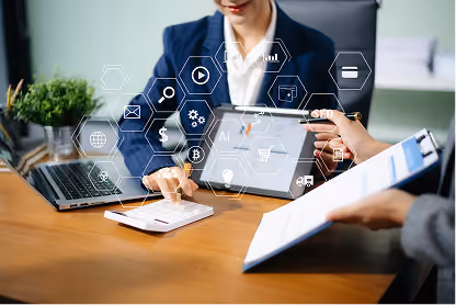 Two business people working with tablet, calculator, laptop, and digital business icons overlay.