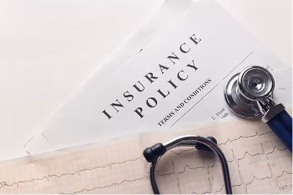 Stethoscope on health insurance policy documents with an ECG printout below on white background.