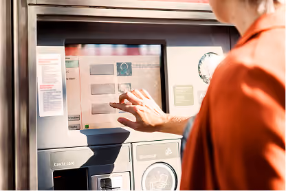 Person selecting options on a touchscreen of a ticket or payment kiosk outdoors.