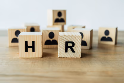 Wooden blocks on table with letters H and R and icons of people in background.