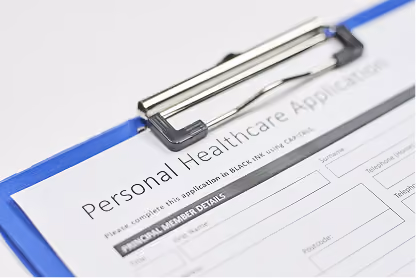 Close-up of a personal healthcare application form clipped on a blue clipboard.