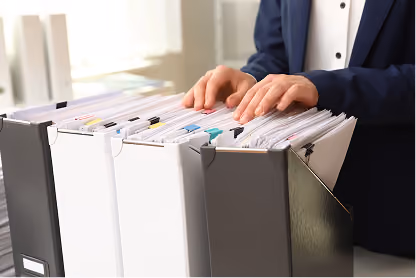 Person organizing documents in a desk file organizer with white and black folders.