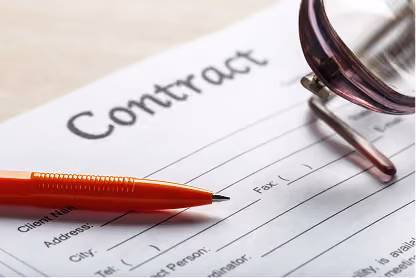 Red pen and magnifying glass on a contract document with blank signature and fax fields.