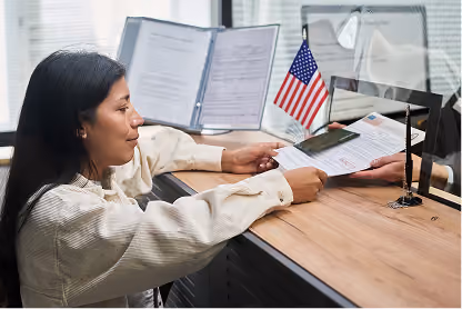 Woman handing over documents at a counter with an American flag visible on the desk.