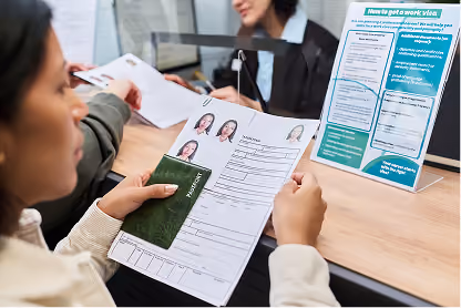 Woman holding passport and application form at a counter with a visa information display.