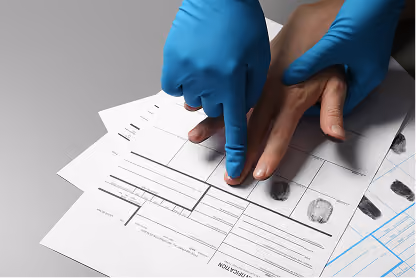 Person wearing blue gloves helps place finger on fingerprint form for identification.