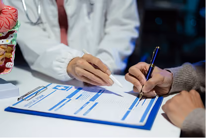Doctor explaining and writing on a medical form held on a blue clipboard for a patient.