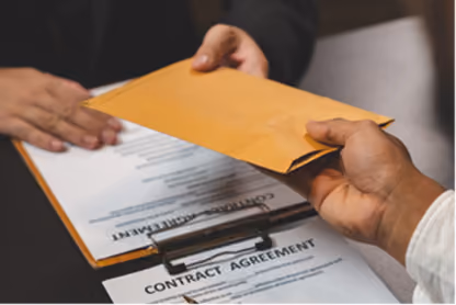 Two people exchanging a large brown envelope over a contract agreement on a clipboard.