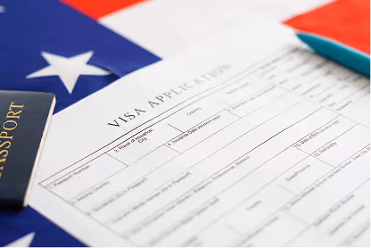 Visa application form on American flag background with a passport and a pen nearby.
