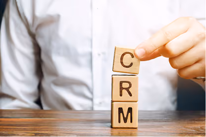 Person stacking wooden blocks with letters C, R, and M on a wooden table.