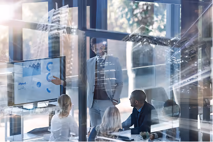 Businessman in suit presenting data on screen to colleagues in modern glass office.