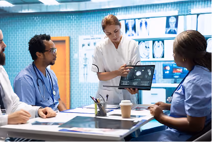 Medical professionals in discussion reviewing brain scans on a laptop in a conference room.