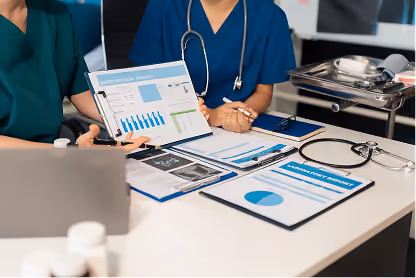 Medical professionals reviewing ultrasound and blood pressure report charts at a desk.