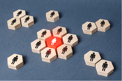 Central white figure surrounded by black figures on hexagonal wooden pieces on blue background.