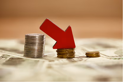 Stacks of coins decreasing in size with a red downward arrow on the middle stack.