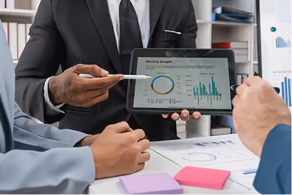 Businessman showing tablet with monthly budget charts to colleagues in a meeting.