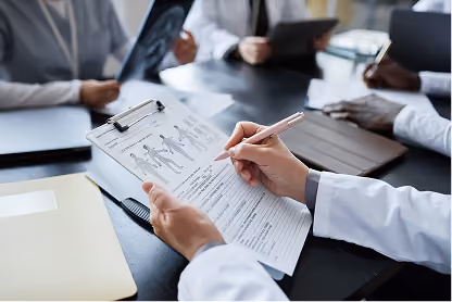 Doctor holding a clipboard with patient forms, surrounded by colleagues reviewing medical documents.
