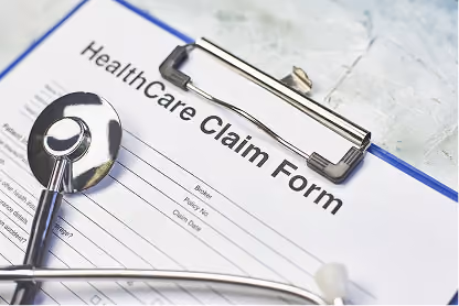 Stethoscope resting on a healthcare claim form clipped to a blue clipboard.