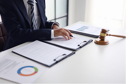Person in suit reviewing documents at desk with a wooden gavel nearby.