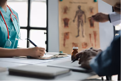 Doctor with stethoscope taking notes while patient sits across, anatomy chart and medicine bottle visible.