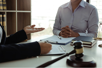 Two professionals in a meeting discussing documents with a gavel on the desk in the foreground.