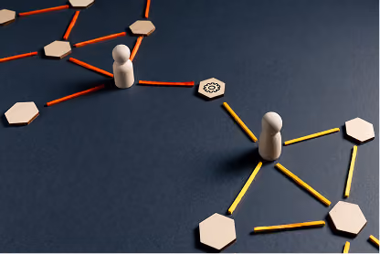 Wooden game pieces connected by colored sticks on a dark surface representing a network or teamwork.