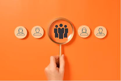 Hand holds magnifying glass focusing on a group icon among individual user icons on orange background.